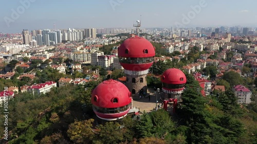 Rotating drone flight of oddly shaped observation towers on hilltop park, contrasting with colonial era architecture in Qingdao, travel destinations China