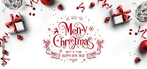 Merry Christmas and New Year text on white background with gift boxes, ribbons, red decoration, bokeh, sparkles and confetti. Xmas greeting card, bokeh, light. Flat lay, top view