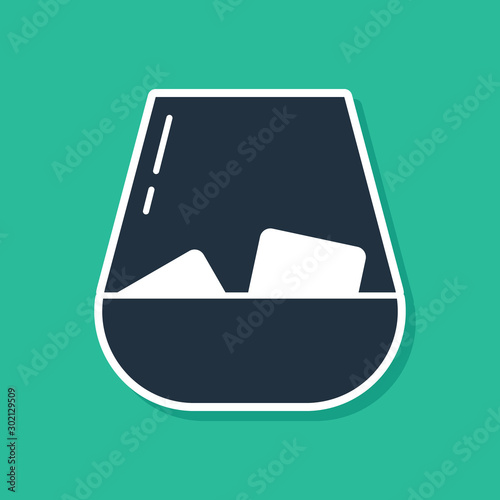 Blue Glass of whiskey and ice cubes icon isolated on green background. Vector Illustration