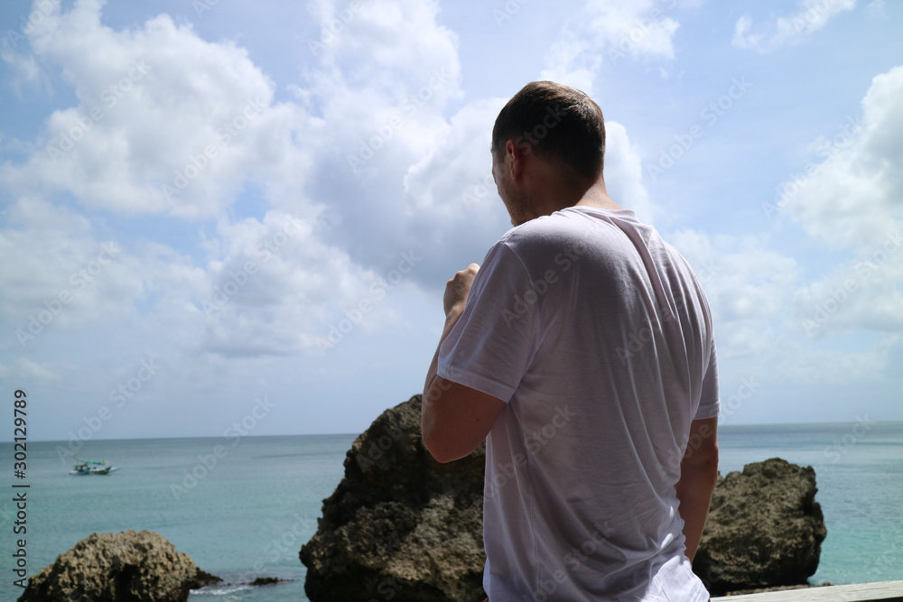A man drinking on holiday while looking out to sea