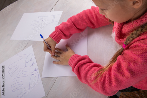 Girl draws at the table, view from the top