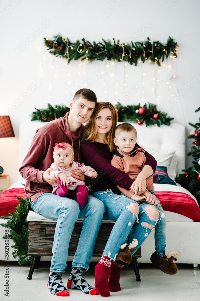 The father, mother holds little son and daughter near Christmas tree. Happy New Year and Merry Christmas. Christmas decorated interior. The concept of family holiday. Close up.