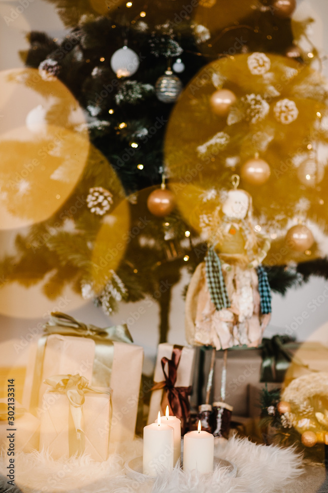 Bokeh. Decorated Christmas interior. Christmas tree with gifts boxes and candles in a room. Fir-tree decorated with garlands. Decor. The concept of winter holiday.