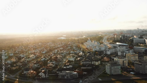 Drone flying above inner suburb house district, city buildings and parks panorama in Minsk, Belarus during sunrise.