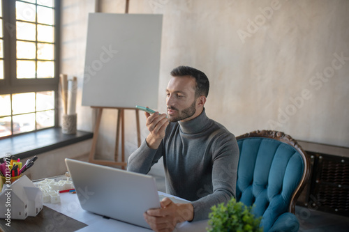 Bearded businessman recording voicemail for wife photo