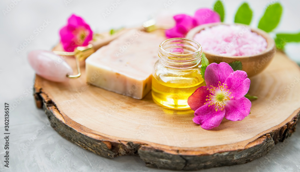 Spa skincare setting with oils and natural soap, rosehip oils and flowers, natural spa still life