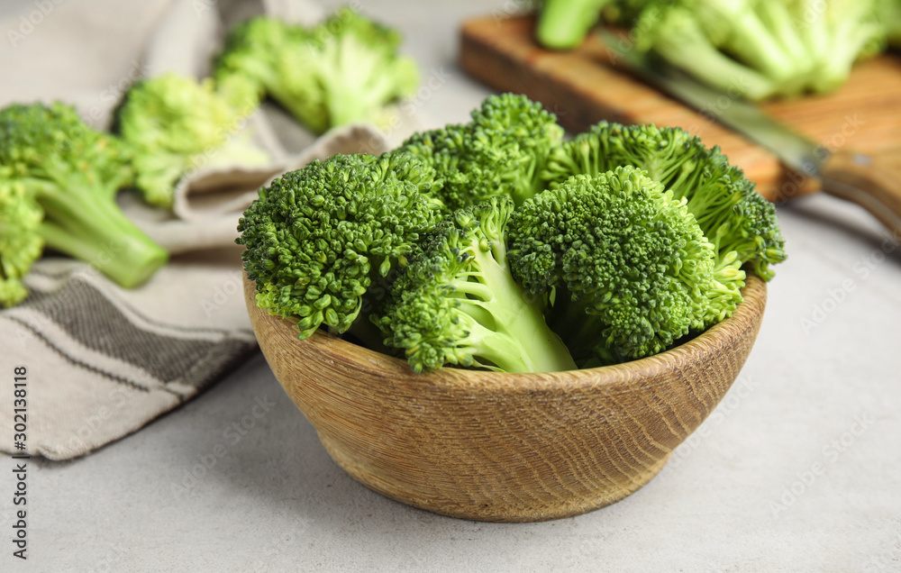 Fresh green broccoli in wooden bowl on light table Fresh green broccoli in wooden bowl on light table