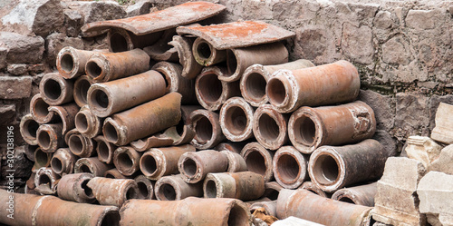 Ancient Roman sewer pipes stacked against a stone wall