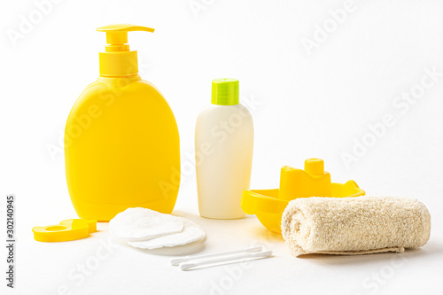 Mock up of baby bath products: bottles for shampoo (shower gel, lotion, oil), towel, cotton buds and pads on white background. Close up, copy space for text. Concept of baby bath accessories