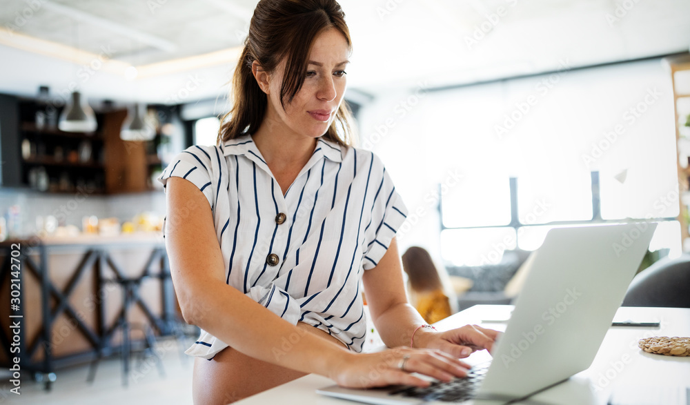 Obraz premium Pregnant woman working from home. Career and pregnancy concept