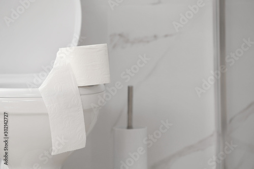 Paper roll on toilet bowl in bathroom