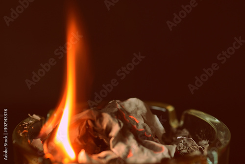 Cuadro en lienzo A crumpled sheet of paper burns in a glass ashtray. Retro style