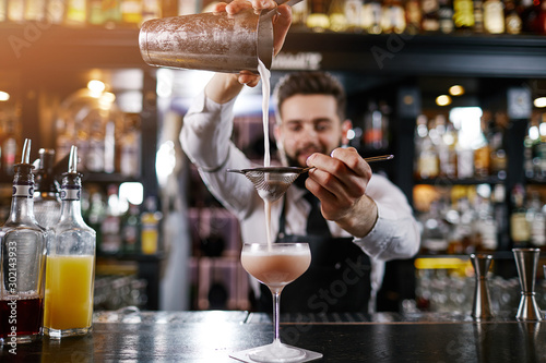 Professional bartender is making cocktail at night club