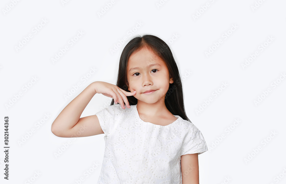Portrait of little Asian kid girl keeping finger on cheek isolated on white background.