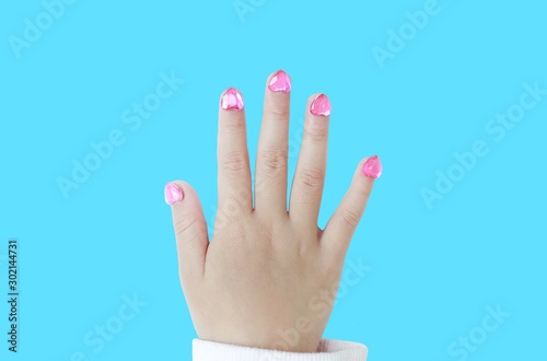 Kid nails with fashion jewels isolated on cyan background. Close up shot.