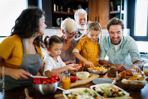 Cheerful family spending good time together while cooking in kitchen photo