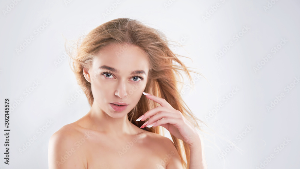 Portrait of beauty model with natural nude make up and touching her face. Spa, skincare and wellness. Close up, Gray background, copyspace. hair fluttering in the wind