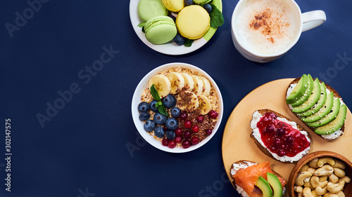 breakfast top view black background. oatmeal with berries, toasts on a wooden tray, nuts, coffee
