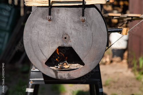 Vintage Drum Barrel Charcoal BBQ in garden.Old Barbeque  with open fire.  Retro Flaming Coals Offset Smoker BBQ. Concept of summer grilling, barbecue, bbq and party. 