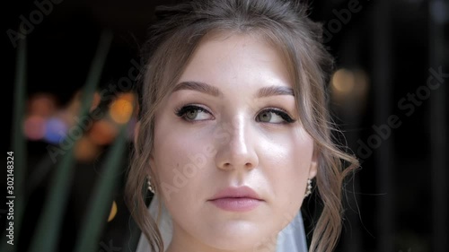 pretty green eyed bride with elegant earrings and hair locks on dark background at wedding ceremony closeup slow motion photo