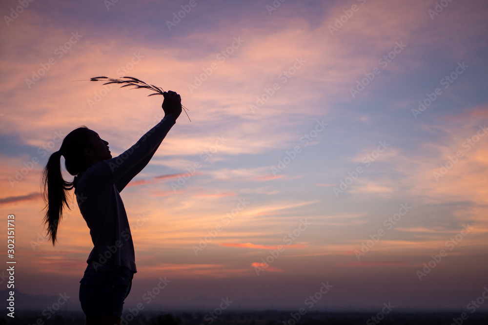 Happiness woman stay outdoor under sunlight of sunset,hold her flower.