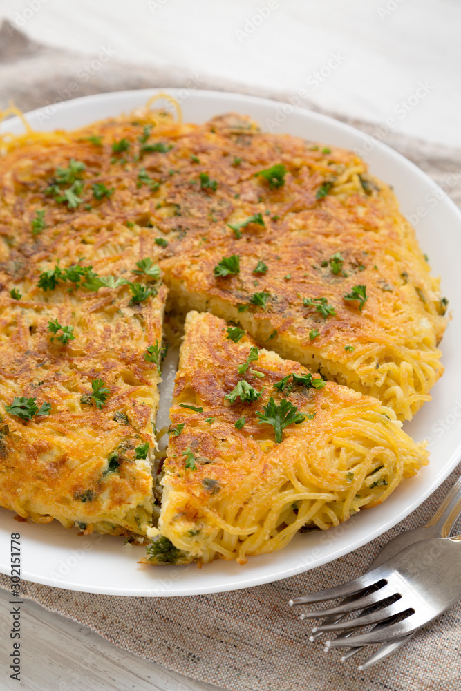 Homemade spaghetti omelette on a white plate, low angle view. Closeup. Homemade spaghetti omelette on a white plate, low angle view. Closeup.