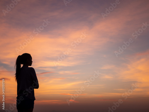 Silhouette of young beautiful woman in  coat, posing at sunset, side view. Looking at right, copy space. © max_play