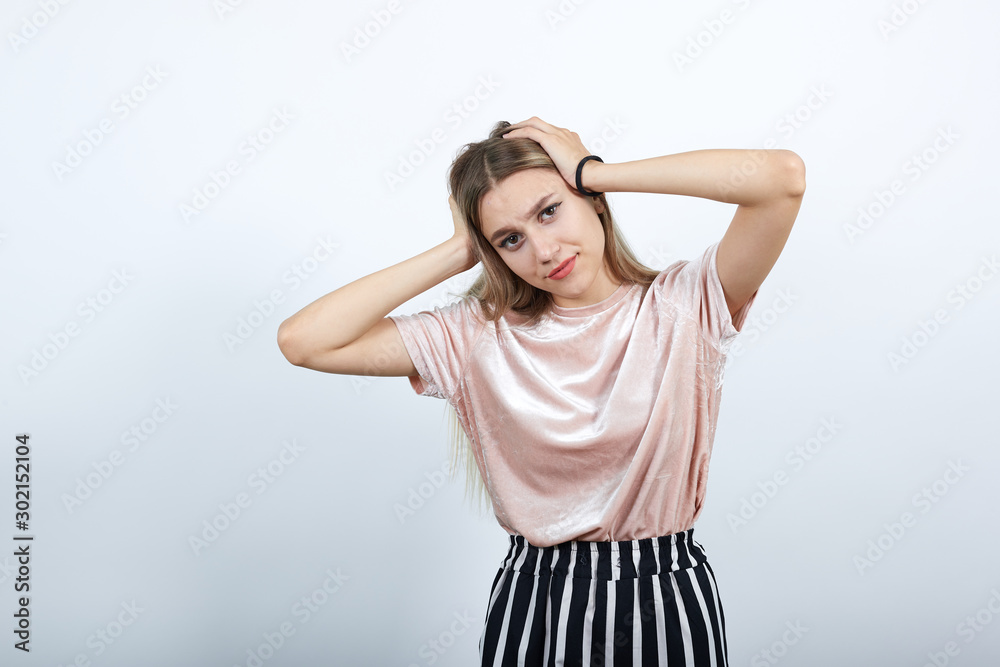 Relaxed young woman in casual clothes keeping eyes opened, with hands behind head isolated on white wall background in studio. People sincere emotions, lifestyle concept. Relaxed young woman in casual clothes keeping eyes opened, with hands behind head isolated on white wall background in studio. People sincere emotions, lifestyle concept.