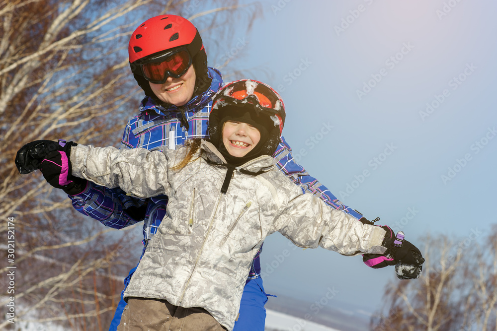 Mom and daughter, in ski equipment play with snow