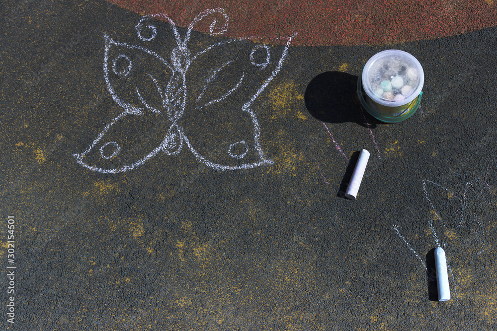 Butterfly drawing on blackboard. Drawing butterfly on the pavement with colored crayons. Children's art, street.