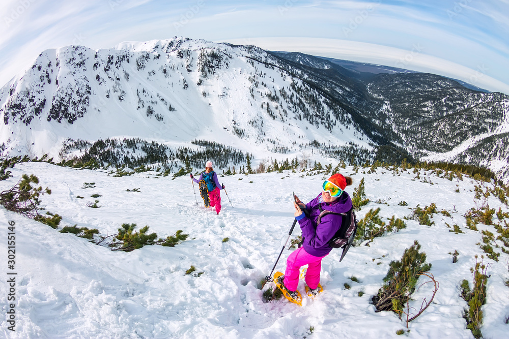 Woman hikeing in the snowy mountains with a phone and snowshoes. and backpack Woman hikeing in the snowy mountains with a phone and snowshoes. and backpack