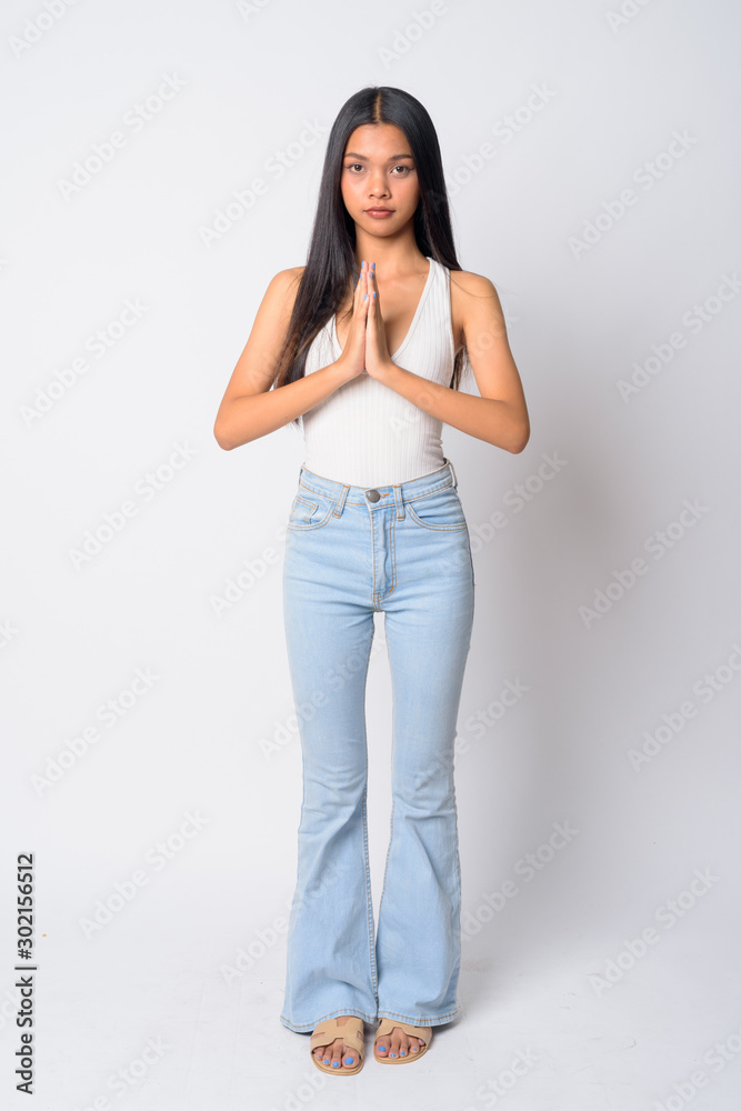 Full body shot of young beautiful Asian woman with Wai as Thai greeting Full body shot of young beautiful Asian woman with Wai as Thai greeting