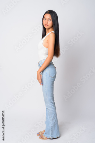 Full body shot profile view of young beautiful Asian woman looking at camera