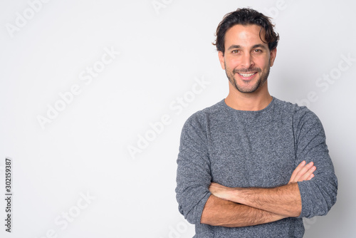 Portrait of happy handsome Hispanic man smiling with arms crossed