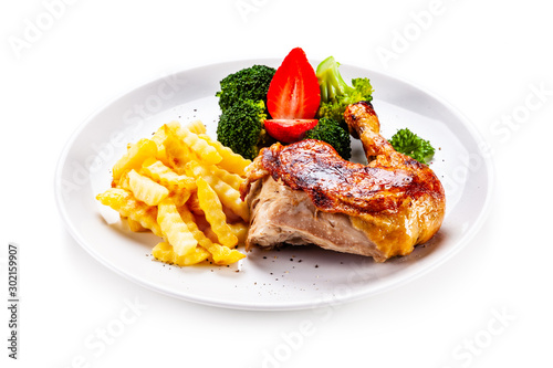 Grilled chicken leg with chips and vegetables on white background