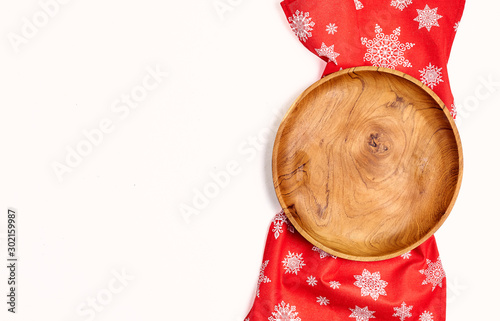 Creative background consisting of a wooden plate, on a kitchen towel on a blue background, christmas colors top view.