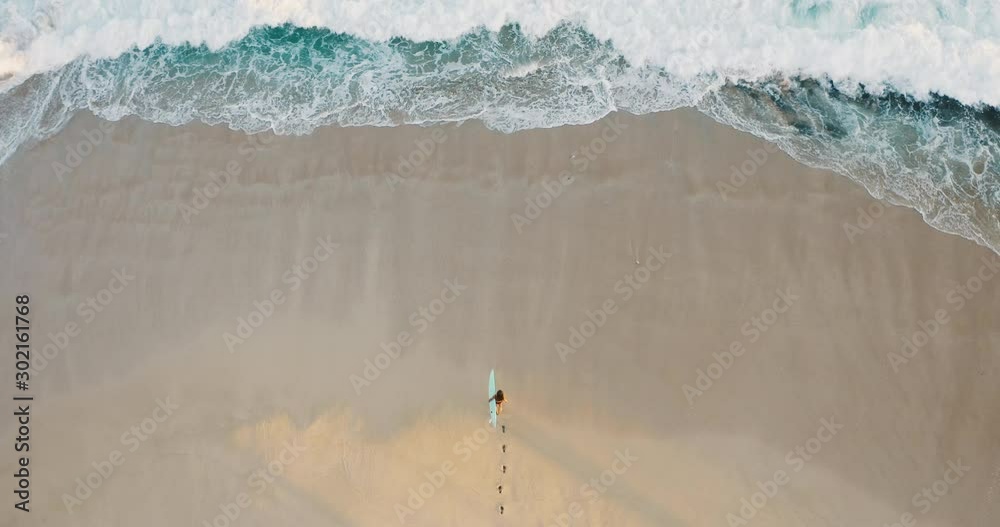 Aerial view of a woman on the beach going surfing