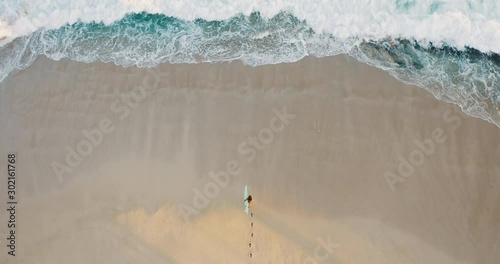 Aerial view of a woman on the beach going surfing