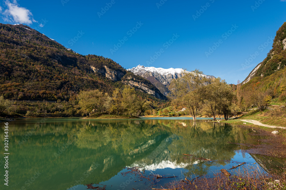 Fototapeta premium Lago di Tenno, small and beautiful lake in Italian Alps with an island and snow-capped peaks. Trento province, Trentino-Alto Adige, Italy, Europe