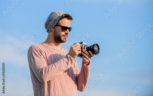 Photojournalist concept. Guy photographer outdoors sky background. Hipster reporter taking photo. Manual settings. Travel blogger. Professional photographer. Handsome photographer guy retro camera