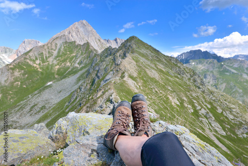 foot and legs of a hiker sitting at the top of alpine mountain