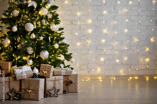 christmas tree and heap of gift boxes - copy space over white brick wall with lights