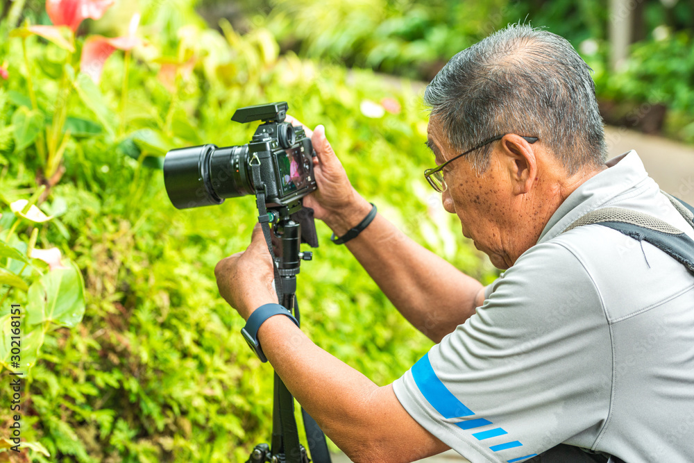 Active Asian Chinese senior male man taking photographs with his digital DSLR camera
