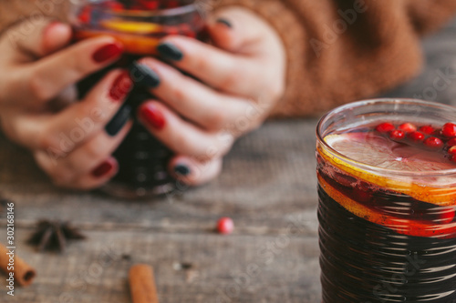 Woman's hands in warm sweater holding a cup of mulled wine
