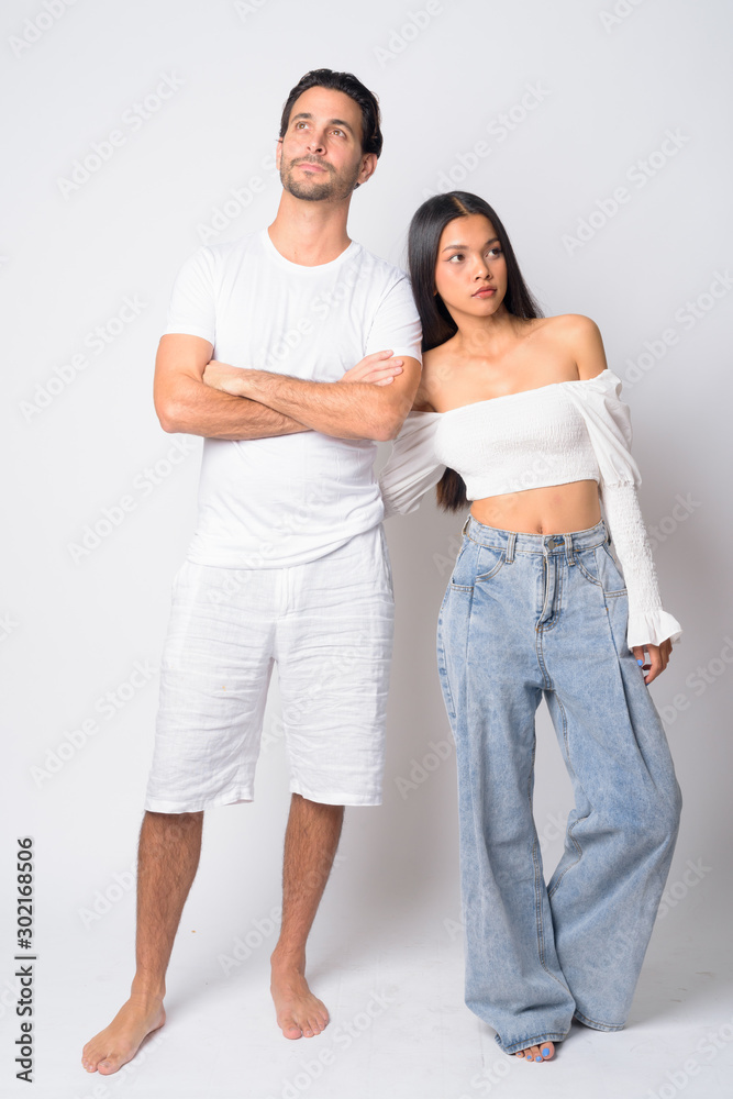 Full body shot of multi ethnic couple thinking together Full body shot of multi ethnic couple thinking together