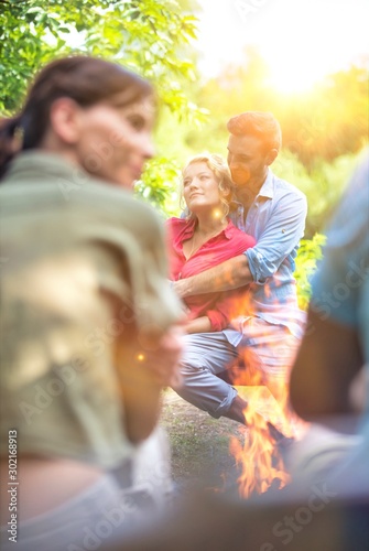Young couple sitting on bench by campfire at park