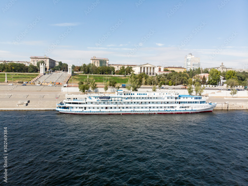 A cruise ship with tourists on the Volga stands at the pier on the central promenade of the city of Volgograd. Panorama of Volgograd. Repair of the waterfront. Russia