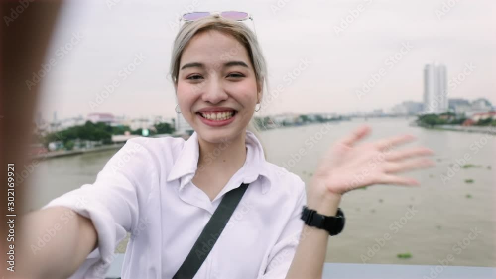 Point of view shot of young Asian woman video chatting with her friends while standing on the Rama VIII Bridge in Thailand.