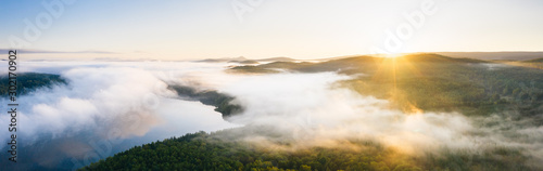 Fog over lake and taiga forest at sunrise, aerial view wide panorama. Nature landscape in Ural, Russia photo