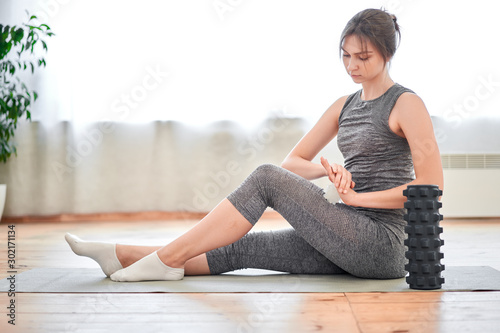 Athletic brunette in training with massager sitting on rug